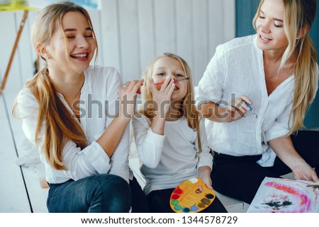 Beautiful little girl painting. Mother drawing with two girl. Family in a studio