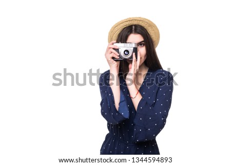 POrtrait of joyful woman wearing big straw hat photographing on photo camera over white background