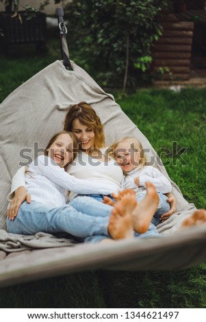 mother with children having fun in a hammock. Mom and kids in a hammock. The family spends time with the children in the garden.