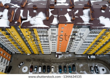 Aerial winter top view of tall apartment building, brick chimneys, tiled roof. Urban infrastructure, view from above.