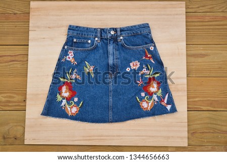 floral embroidered ,bird pattern skirt jeans on wooden background 


