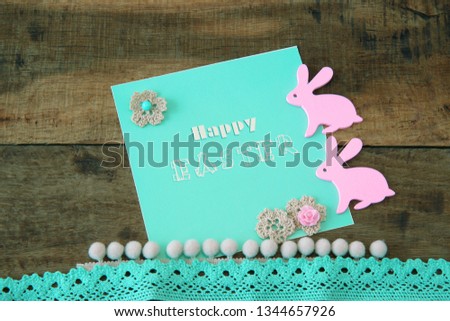 Card with an inscription Happy Easter and a pink rabbit	on a wooden background