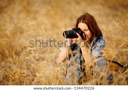female photographer in the field with a camera taking pictures