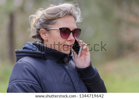 image of woman in sunglasses talking on a mobile phone in the forest