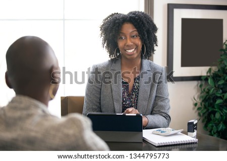 Black female businesswoman in an office with a client giving legal advice about taxes or financial loans. The woman could be a lawyer or a cpa accountant. Royalty-Free Stock Photo #1344795773