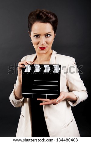 Woman with movie clap over black background
