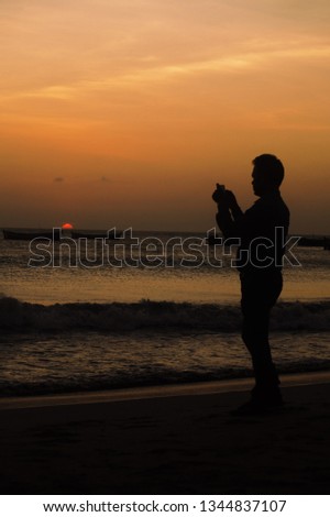 Silhouette of a man taking pictures of the setting sun, boats and sea. Dhanushkodi Beach  Rameshwaram