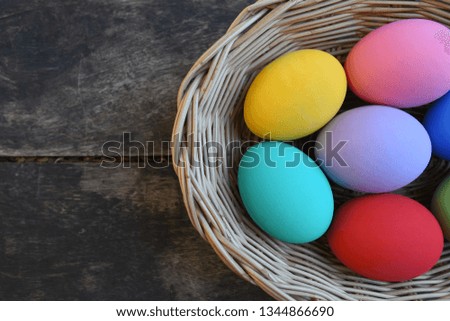 Colorful eggs in a basket on a wooden background