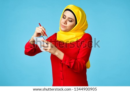 arab woman writing in notebook on a blue background                              