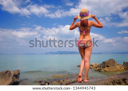 Free action and relaxing of bikini tanned girl on the rock at Krabi, Thailand. Concept image for summer vacation in tropical country.