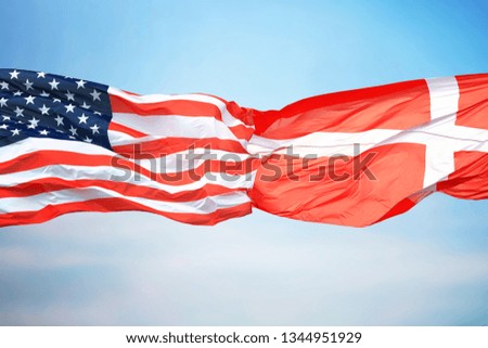 Flags of the USA and Denmark against the background of the blue sky