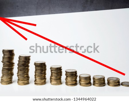 Piles of coins with red decreasing arrow on top.