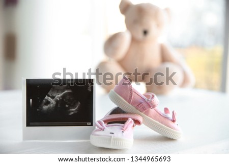 Ultrasound photo of baby and cute boots on table indoors