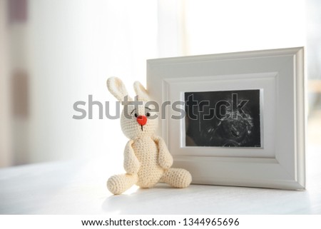Ultrasound photo of baby and toy on table indoors, space for text