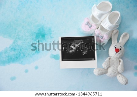 Ultrasound photo, baby shoes and toy on color background, top view with space for text