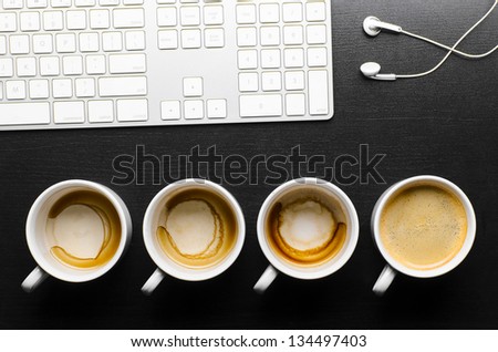 working hours. empty and full cups of fresh espresso with keyboard and headphones, view from above