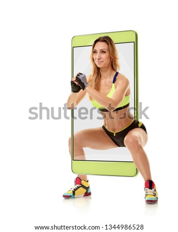 Portrait of young fit sporty woman doing squat, concept virtual reality of the smartphone. going out of the device