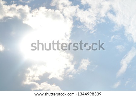 The sun is covered in white clouds with blue sky on a sunny day