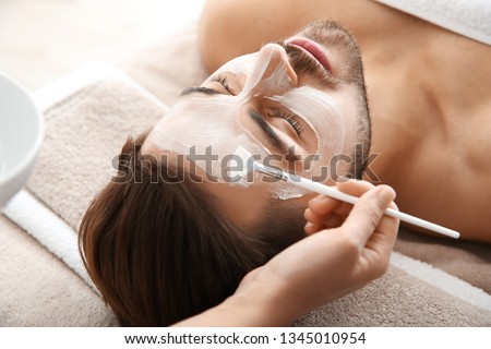 Cosmetologist applying mask on client's face in spa salon Royalty-Free Stock Photo #1345010954