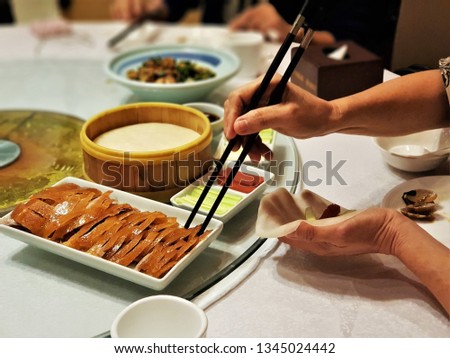 A woman eating Peking roast duck in the restaurant. A delicious Peking roast duck is the most famous gourmet cuisine of Beijing, good-taste local food and one of the most popular foods in China.