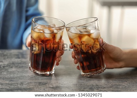 Women holding glasses of cola with ice at table, closeup Royalty-Free Stock Photo #1345029071