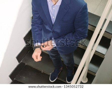Man in blue blazer jacket walking down on stairs while fixing sleeve