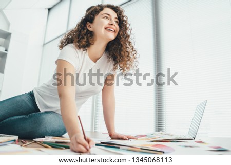 The woman sitting on the table and drawing on a paper 