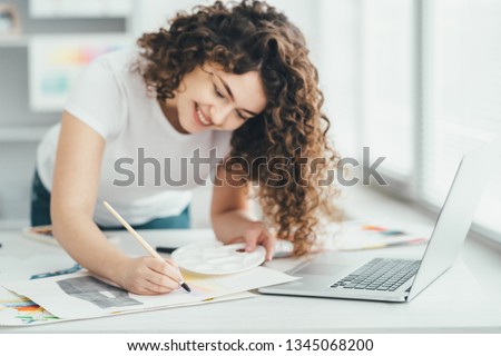 The happy woman with a brush painting a picture at the table