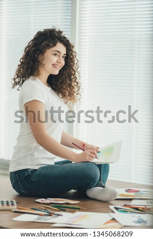 The beautiful woman sitting on the table and drawing on the paper