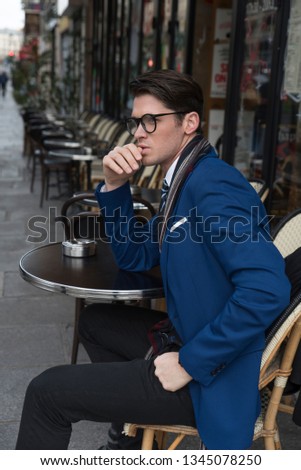 Street fashion concept. Portrait of elegant young handsome man. Paris buildings as background.