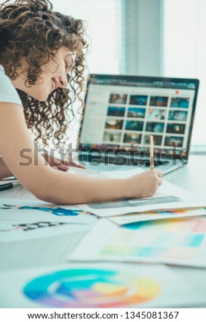 The happy woman painting a picture near the laptop