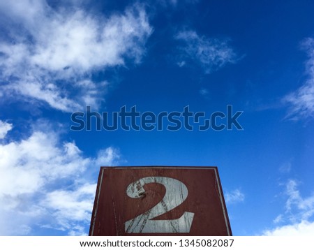 White 2 Arabic numbers in brown label on a cloudy sky background