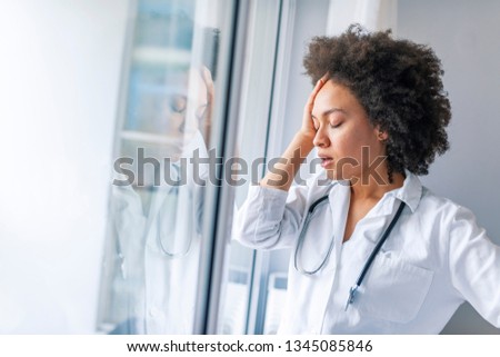 Nurse doctor with migraine overworked, overstressed isolated background hospital hall corridor. Tired female doctor near window in hospital. It's a stressful profession 