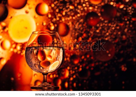 transparent glasses with water with oily drops on colorful background 