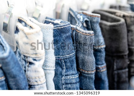 Many blue jeans on hangers for sale in local street market in Thailand, close up