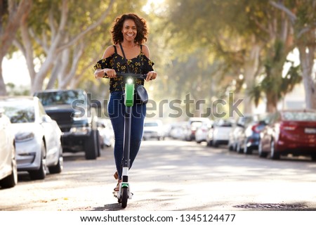 Full length shot of millennial black woman riding an electric scooter in the street Royalty-Free Stock Photo #1345124477