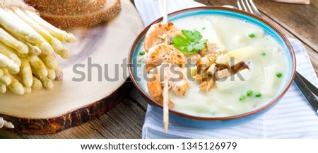 close-up view of gourmet asparagus soup with shrimp skewers and fresh asparagus on table    