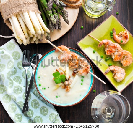 close-up view of gourmet asparagus soup with shrimp skewers and fresh asparagus on table    