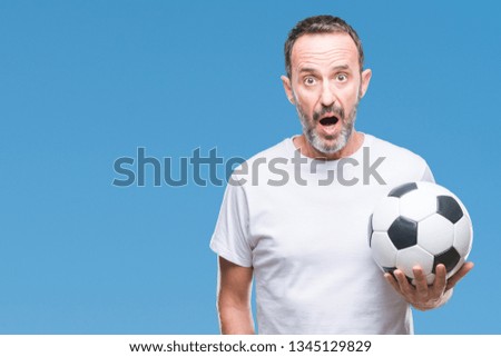 Middle age hoary senior man holding soccer football ball over isolated background scared in shock with a surprise face, afraid and excited with fear expression