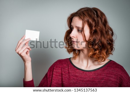 cute red-haired girl holding a sticker, isolated on gray background