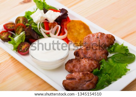 Tasty  balkan minced meat kebapcheta served with onion,  tomatoes, lettuce and sauce