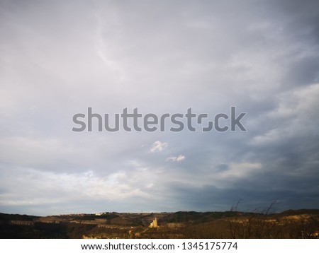 Photo capturing the glowing silhouette of a yellow stone castle, sitting on a hilltop, under the threatening sky of an approaching thunderstorm.