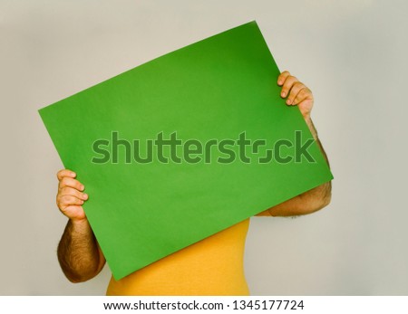 man hid behind a green sheet of paper, Whatman . male wear yellow . no face. isolated on white or gray wall background. 
