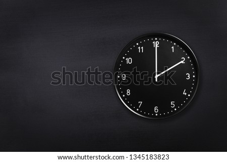 Black wall clock showing two o'clock on black chalkboard background. Office clock showing 2am or 2pm on black texture