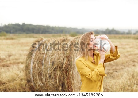 Modern portrait of woman with stack hay and with jug of milk. Nature background.