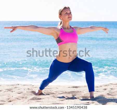 Woman 28-35 years old is practicing yoga on the beach near sea.  Royalty-Free Stock Photo #1345190438