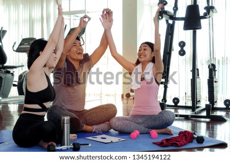 group of young sporty people cheer up and laughing together sitting on yoga mat in fitness gym after workout, exercise at morning, encouragement, training, partnership, success and teamwork concept Royalty-Free Stock Photo #1345194122