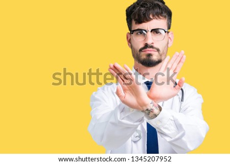 Young doctor man wearing hospital coat over isolated background Rejection expression crossing arms and palms doing negative sign, angry face