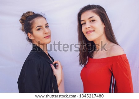 Two young beautiful girls posing on white background