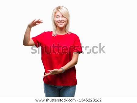 Young beautiful blonde woman wearing red t-shirt over isolated background gesturing with hands showing big and large size sign, measure symbol. Smiling looking at the camera. Measuring concept.